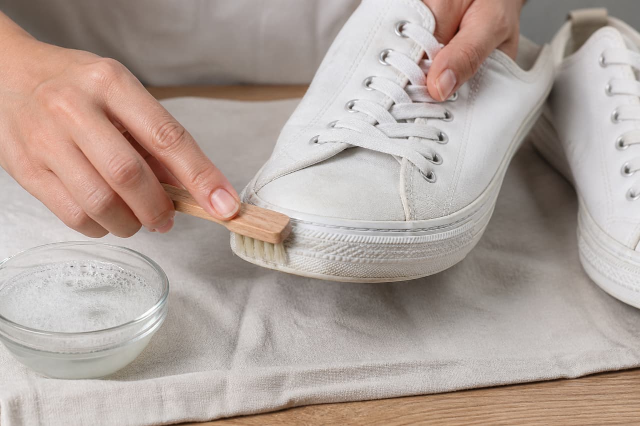 Zapatillas blancas usadas mientras se limpia la suela con un cepillo suave
